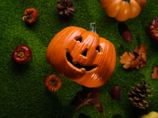 Creative composition for Halloween. On the green grass there is a round dance of small pumpkins and one big orange pumpkin with a nice smile. The concept is the celebration of Halloween.
