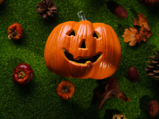 Cheerful orange smiling pumpkin surrounded by small pumpkins on green grass. Background - Halloween. Congratulation, invitation, banner, advertisement, postcard.