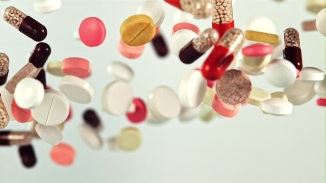 A bunch of different pills fly up and fall down. On a white background. Filmed on a high-speed camera at 1000 fps. 