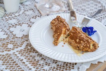 Homemade puff pastry deep fried Eclairs with vanilla cream topping with almonds nut on white plate over table top with lace tablecloth. traditional french dessert. selective focus