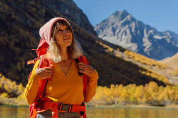 Hiker happy woman at lake in autumnal mountains. Mountain lake and tourist