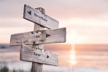 brother in law text quote on wooden crossroad signpost outdoors on beach with pink pastel sunset colors. Romantic theme.