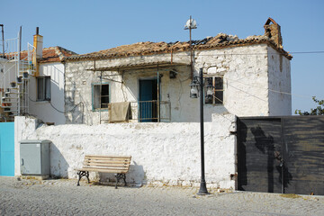 An old white farmhouse exterior. Ancient rustic house on the street with a broken damaged roof,...