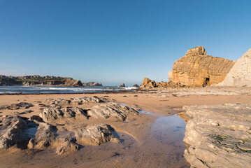 Beautiful landscape of the lonely rocky beach of Portio on a cloudless morning with blue sky, Costa Quebrada, Liencres, Cantabria, Spain