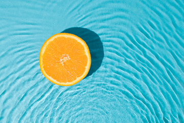 Minimal summer flat lay with half fresh oranges in fresh sunny water. Creative organic fruit background.