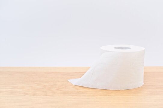 Toilet Paper Roll On A Bright Wooden Table With White Wall Background