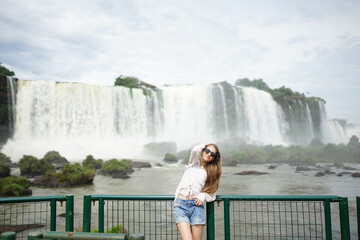 In the photo, a beautiful girl with glasses and white strands in her hair stands against the...