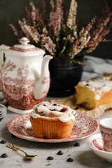 Cinnabon roll with great cream on it, with a tea cup on background and a beautiful background