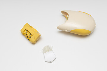 a disassembled epilator along with a brush for cleaning lies on a white