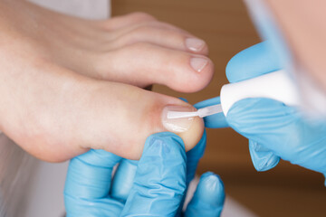 Obraz premium pedicure master applies colorless nail polish