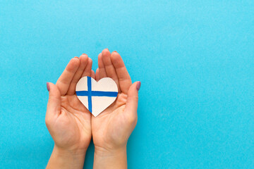 Paper heart in the colors of the flag of Finland in female hands.