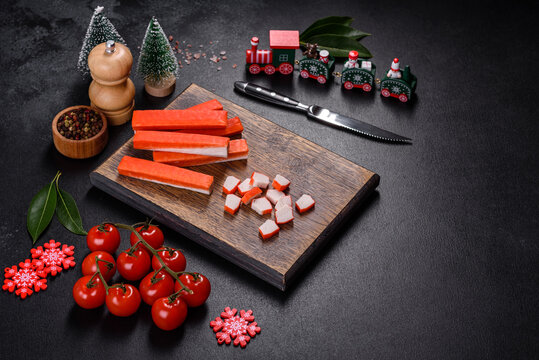 Crab sticks on a cutting Board with a knife. On a black christmas table
