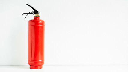 Red fire extinguisher on a white wall background