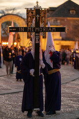 Nazarenes with white caps and the Templar cross carrying the Christian cross in a procession