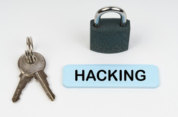 On a white surface there is a lock, keys and a blue sign with the inscription - Hacking