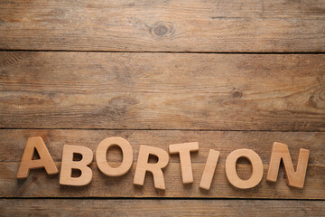 Word Abortion made of letters on wooden background, flat lay. Space for text