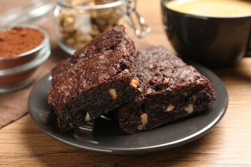 Delicious chocolate brownies with nuts on wooden table, closeup