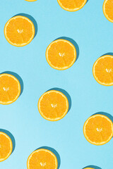 Creative summer pattern with sliced fresh orange on sunny blue background. Flat lay.