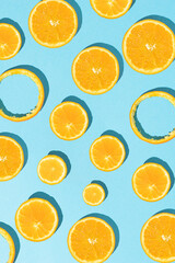 Creative summer pattern with different sliced fresh orange on sunny blue background. Flat lay.