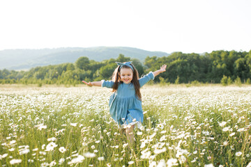 Happy cheerful child girl 3-4 year old wear stylish rustic dress running in meadow with flowers...