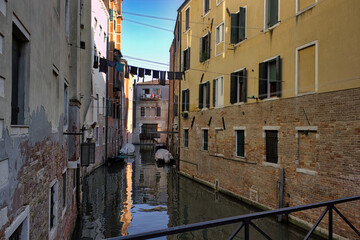 Colorful cloths hanging over a waterway with boats in the island of Venice in Northern Italy, Europe
