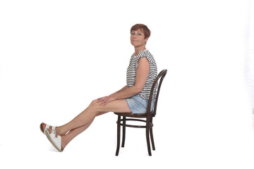 middle aged woman sitting on chair with stretched legs on white background