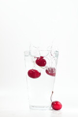 cherries falling into water, splashes, fall into water transparent glass, white background