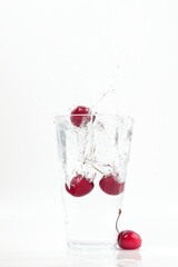 cherries falling into water, splashes, fall into water transparent glass, white background