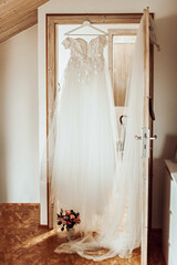 Wedding day. The bride's dress hangs in the doorway