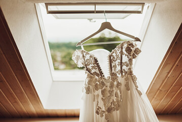Wedding day. The bride's dress hangs in the window opening