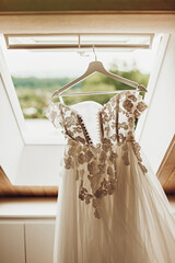 Wedding day. The bride's dress hangs in the window opening