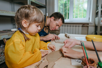 Father and his daughter at a master class in clay modeling
