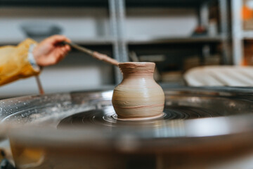 Little girl working with clay on potter's wheel