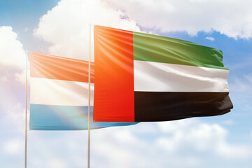 Sunny blue sky and flags of united arab emirates and luxembourg