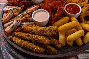assorted beer snacks on the board with sauses on wooden table