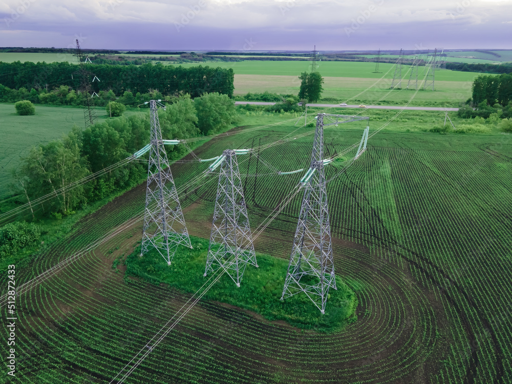 Wall mural high voltage electric power tower in a green agricultural landscape at beautiful sunset