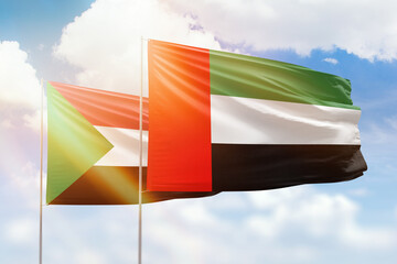 Sunny blue sky and flags of united arab emirates and sudan