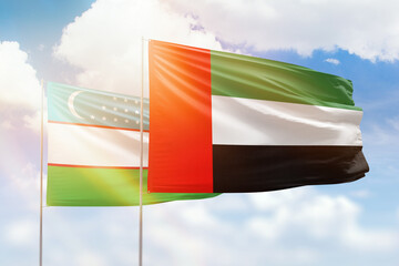 Sunny blue sky and flags of united arab emirates and uzbekistan