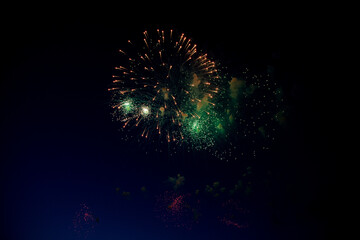 Bright orange fireworks and lots of green sparks on the background of the night sky. High quality photo