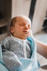 Portrait of newborn boy on mother's hand. Baby boy sleeping in mother's arms. Selective focus. Film grain