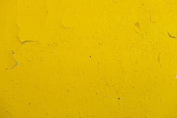 old wall painted with yellow paint with cracks and bubbles