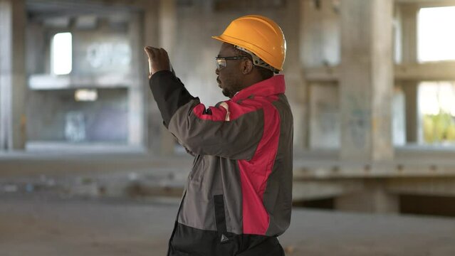 African american workman filming video at construction site. African american worker records videos on his smartphone