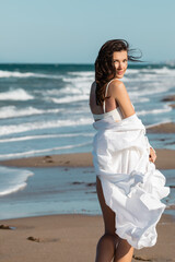 Fototapeta na wymiar young woman in white shirt and swimwear standing near ocean.