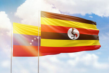 Sunny blue sky and flags of uganda and venezuela