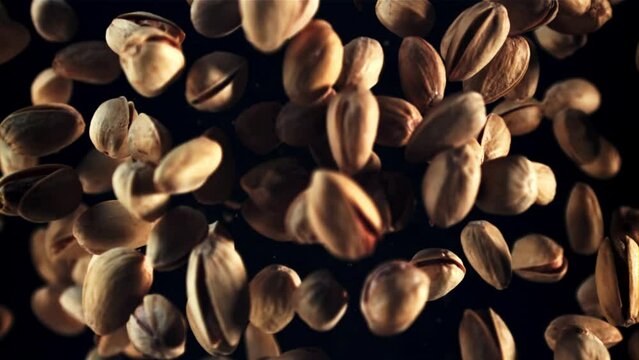 Pistachios rise up and fall down. Top view. On a black background. Filmed is slow motion 1000 fps.