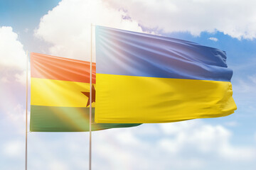 Sunny blue sky and flags of ukraine and ghana