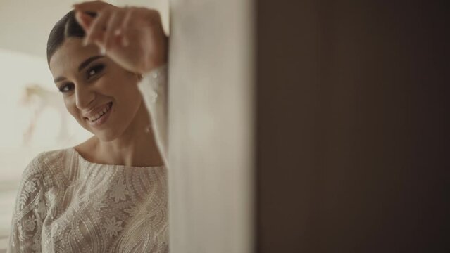 Bride's photo shoot. Portrait of a cute brunette bride. The bride looks out the window and then sensually looks into the camera.