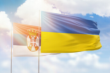 Sunny blue sky and flags of ukraine and serbia