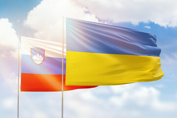 Sunny blue sky and flags of ukraine and slovenia