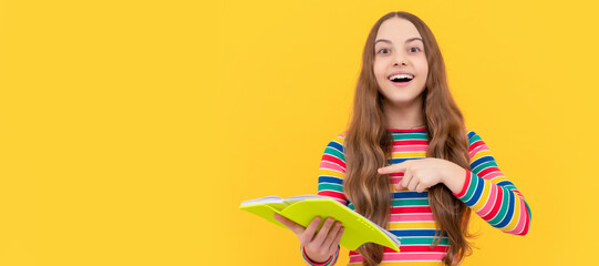 Happy kid smile pointing finger at school book yellow background, study. Banner of schoolgirl student. School child pupil portrait with copy space.